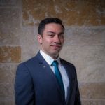 A man in a suit and tie standing next to a wall.