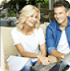 A man and woman sitting on the couch looking at a laptop.
